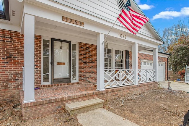 view of exterior entry featuring a garage and a porch