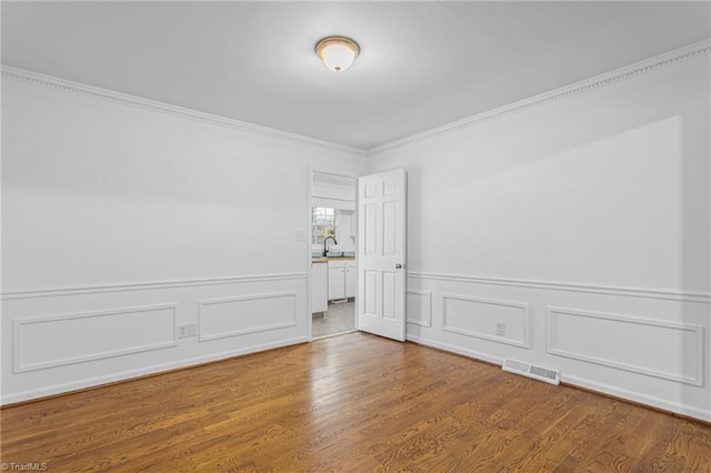 empty room featuring sink, hardwood / wood-style floors, and crown molding