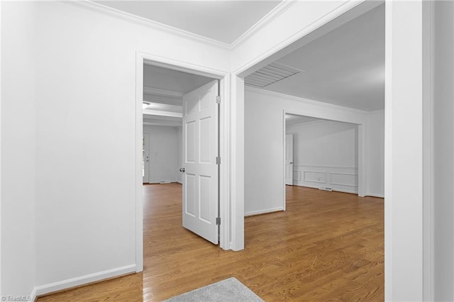 hall with light hardwood / wood-style floors and ornamental molding