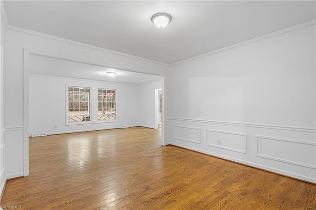 spare room with hardwood / wood-style flooring and crown molding