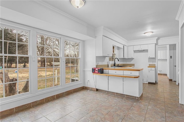 kitchen featuring sink, white cabinetry, kitchen peninsula, and crown molding