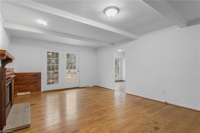 unfurnished living room with ornamental molding, hardwood / wood-style flooring, wood walls, and beam ceiling