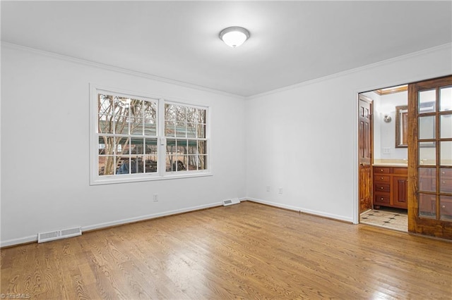 empty room with light hardwood / wood-style floors and crown molding