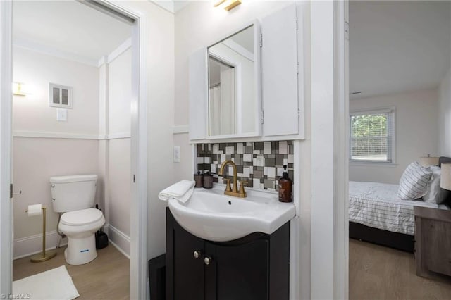 bathroom featuring hardwood / wood-style flooring, vanity, toilet, and backsplash