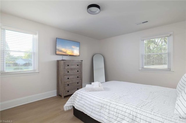 bedroom with multiple windows and light wood-type flooring