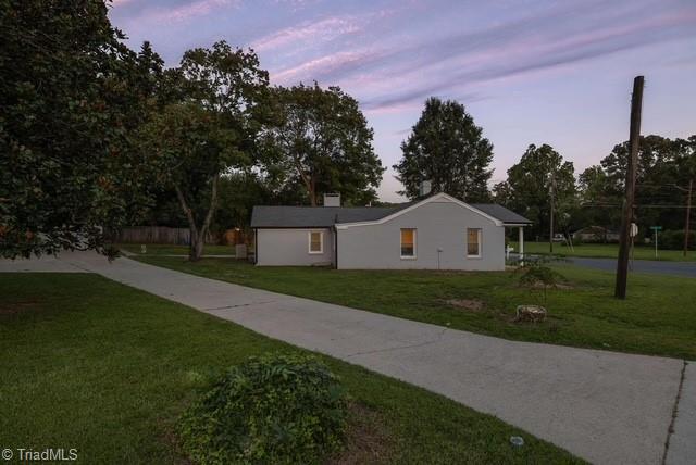 property exterior at dusk with a lawn