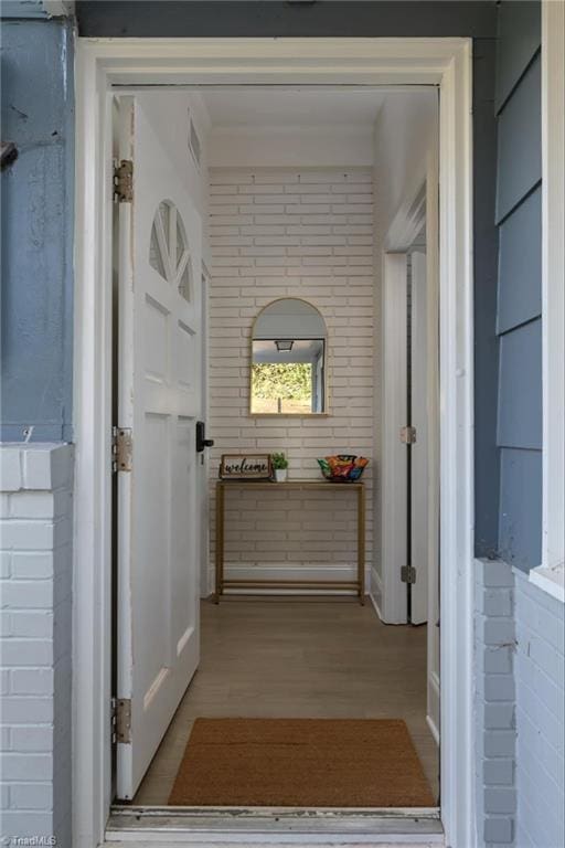 hall featuring light hardwood / wood-style floors and brick wall