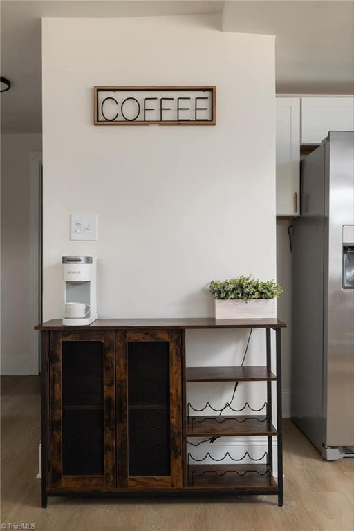 interior details with white cabinets, stainless steel fridge, and light hardwood / wood-style floors