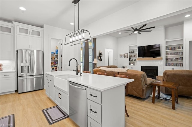 kitchen with white cabinetry, appliances with stainless steel finishes, a kitchen island with sink, and pendant lighting