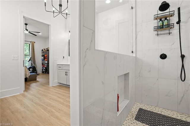 bathroom with ceiling fan, tiled shower, vanity, and hardwood / wood-style floors