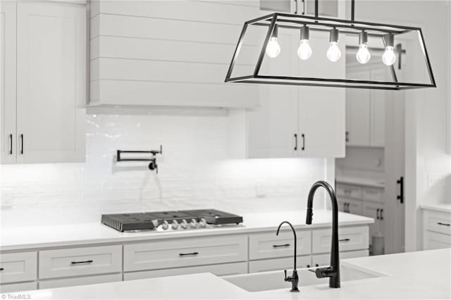 kitchen featuring decorative light fixtures, tasteful backsplash, white cabinetry, stainless steel gas stovetop, and sink