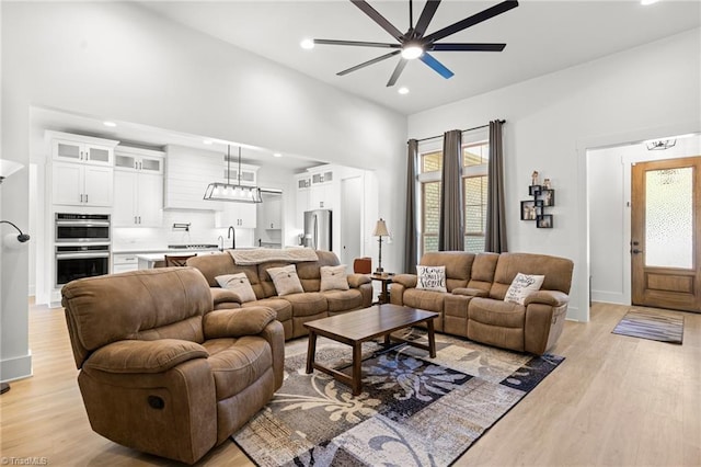 living room featuring ceiling fan, sink, and light hardwood / wood-style flooring