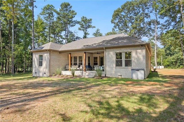 rear view of property featuring ceiling fan, a yard, and covered porch