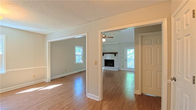 3128 Burke Mill Ct, Winston-Salem, NC 27103 - empty room with wood finished floors, healthy amount of natural light, a textured ceiling, ceiling fan, and a fireplace