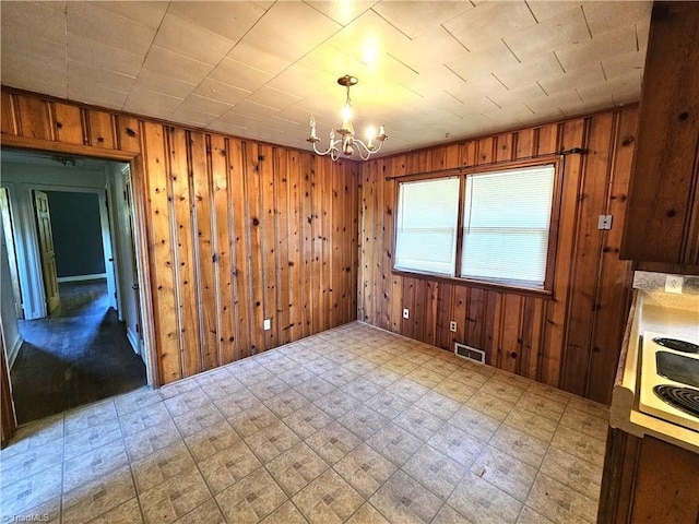 unfurnished dining area with a notable chandelier and wood walls