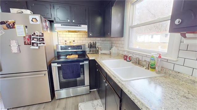 kitchen featuring appliances with stainless steel finishes, light hardwood / wood-style floors, sink, and backsplash