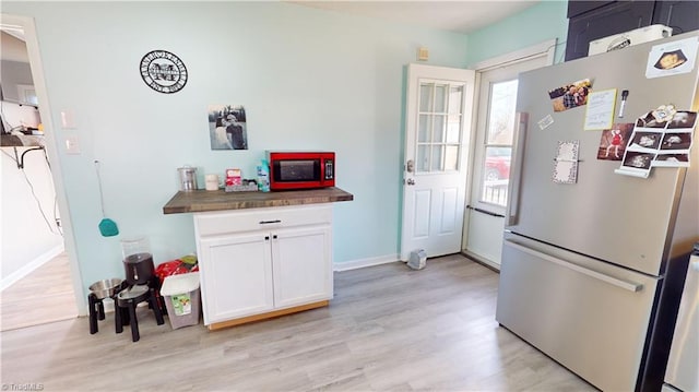 kitchen featuring stainless steel refrigerator, white cabinets, and light wood-type flooring