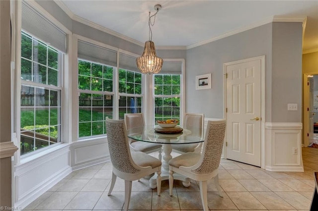 dining room with crown molding, a chandelier, a decorative wall, wainscoting, and light tile patterned flooring