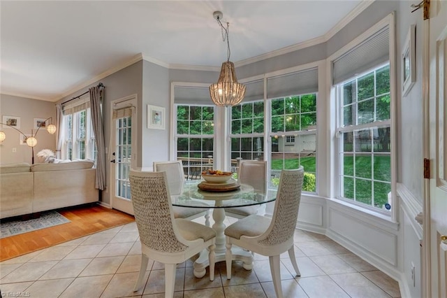 dining space featuring a chandelier, plenty of natural light, light tile patterned flooring, and crown molding