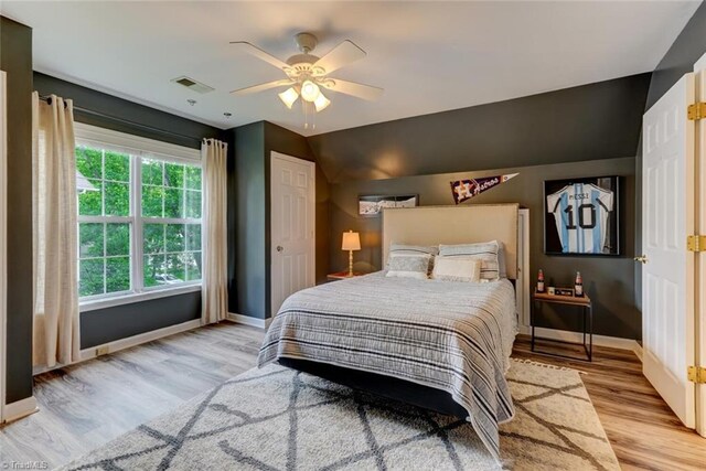 bedroom featuring baseboards, light wood-type flooring, ceiling fan, and vaulted ceiling