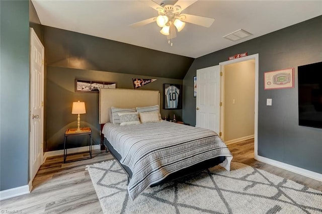 bedroom with light wood finished floors, baseboards, lofted ceiling, and ceiling fan