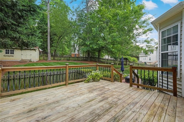 deck with a fenced backyard, an outdoor structure, and a storage unit