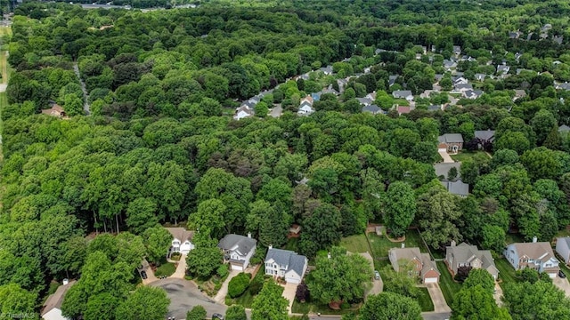 aerial view of property's location featuring a forest and nearby suburban area