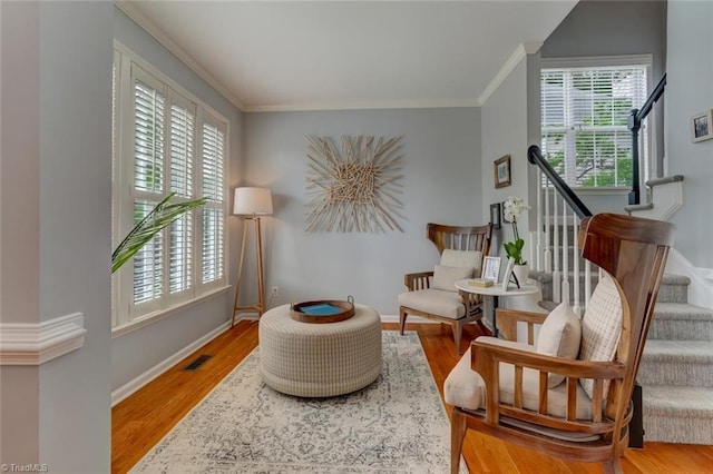 living area with crown molding, stairs, wood finished floors, and baseboards