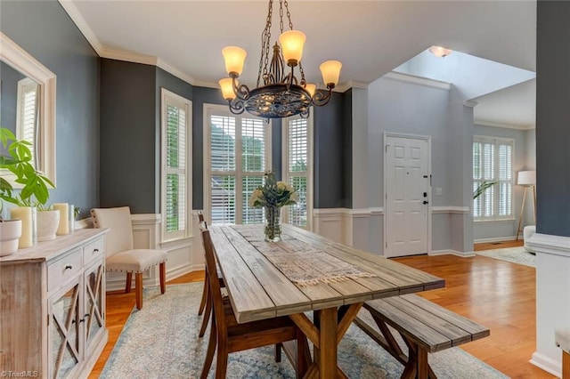 dining area featuring a chandelier, ornamental molding, light wood-style flooring, and healthy amount of natural light