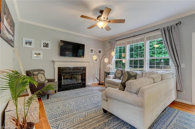living area featuring ceiling fan, wood finished floors, a high end fireplace, crown molding, and baseboards