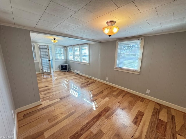 spare room with a wood stove and light hardwood / wood-style flooring