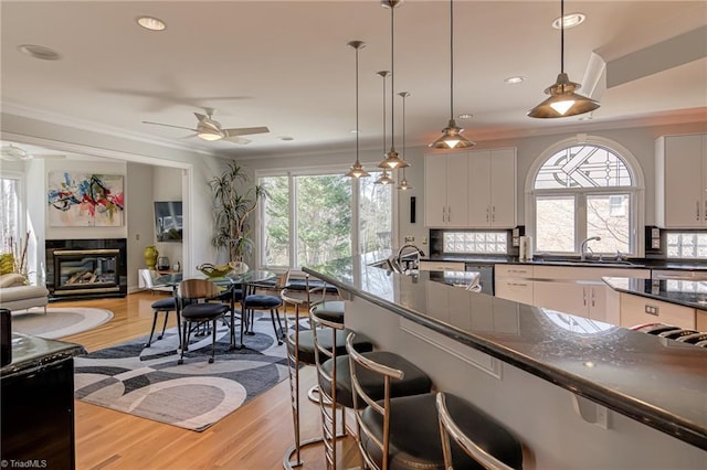 kitchen with a sink, a kitchen breakfast bar, dark countertops, and crown molding