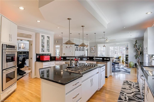 kitchen featuring a peninsula, white cabinets, appliances with stainless steel finishes, and ornamental molding