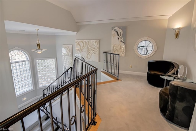 interior space with baseboards, carpet floors, ornamental molding, vaulted ceiling, and an upstairs landing