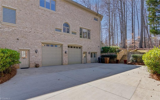 view of property exterior featuring concrete driveway, an attached garage, and brick siding