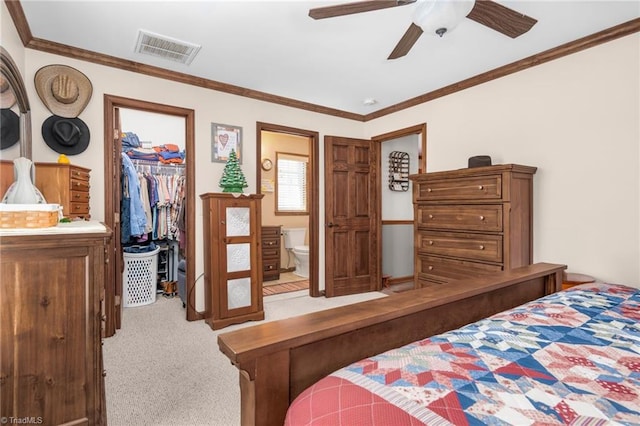 carpeted bedroom featuring a walk in closet, ensuite bath, visible vents, and ornamental molding