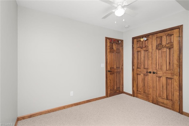 unfurnished bedroom with a closet, carpet flooring, a ceiling fan, and baseboards