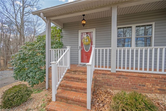 property entrance with a porch and brick siding