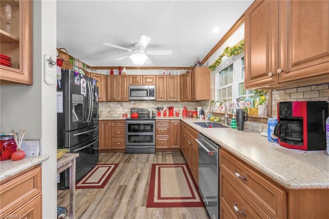 kitchen with decorative backsplash, light wood-style flooring, brown cabinetry, stainless steel appliances, and a sink