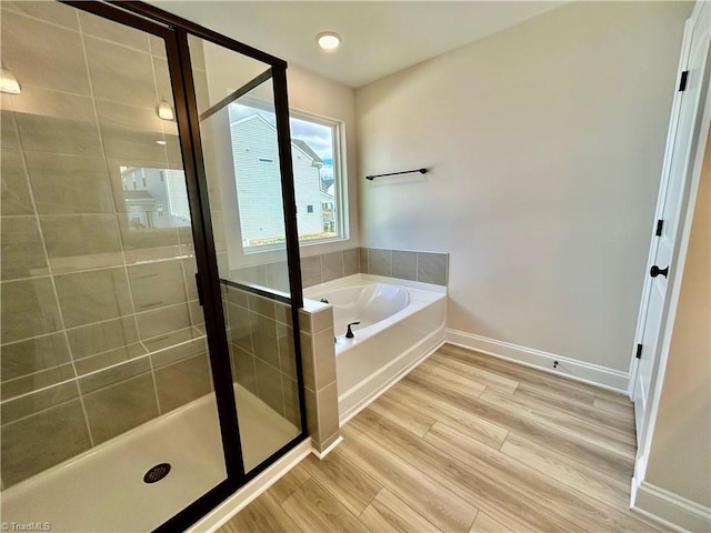 bathroom featuring wood-type flooring and separate shower and tub