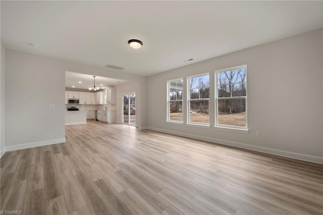 unfurnished living room featuring light hardwood / wood-style floors and a chandelier