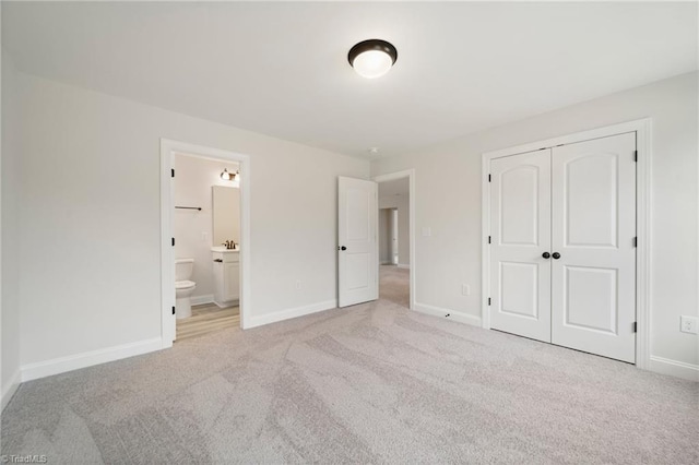 unfurnished bedroom featuring light colored carpet, connected bathroom, and a closet