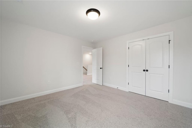 unfurnished bedroom with light colored carpet and a closet