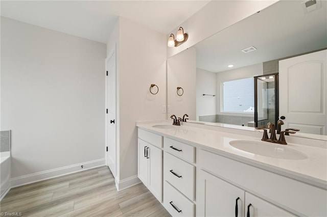 bathroom with walk in shower, vanity, and wood-type flooring