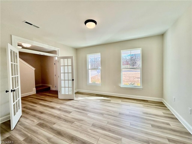 spare room featuring french doors and light wood-type flooring