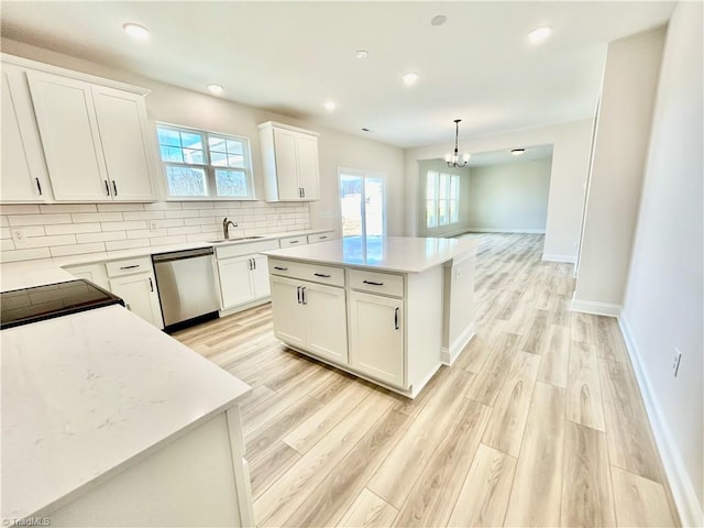 kitchen with dishwasher, a kitchen island, pendant lighting, and white cabinets