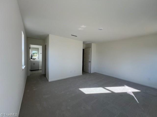 unfurnished room featuring dark carpet