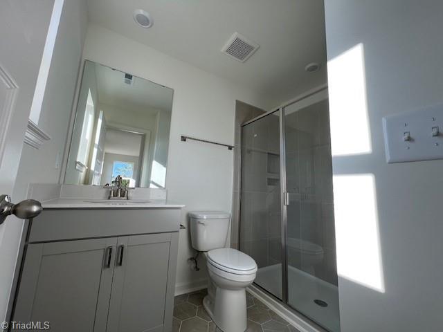 bathroom with vanity, toilet, tile patterned floors, and a shower with shower door