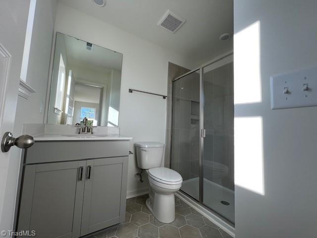 bathroom with vanity, toilet, a shower with shower door, and tile patterned flooring