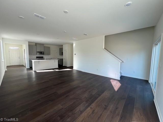 unfurnished living room with dark wood-type flooring